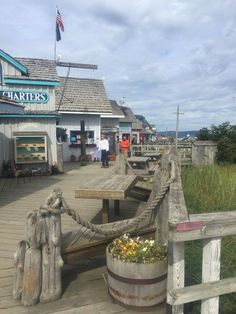 there is a wooden bench on the boardwalk next to a building with people walking around it