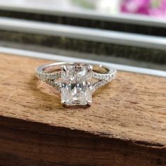 a diamond ring sitting on top of a piece of wood next to a window sill