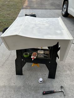 a white tent sitting on top of a cement ground next to a tool and other items