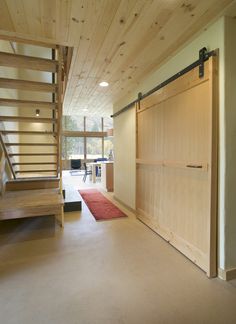 an open living room with stairs leading up to the second floor, and a red rug on the floor