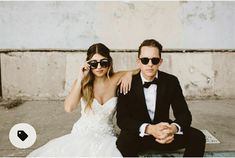 a man and woman sitting on a bench wearing sunglasses