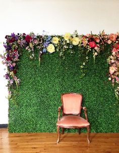 a chair sitting in front of a green wall with flowers on it and a wooden floor