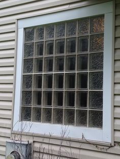 a cat sitting in front of a window on the side of a house