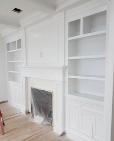 a living room with white walls and built in bookshelves that are being painted