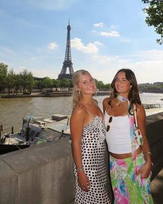 two beautiful women standing next to each other in front of the eiffel tower