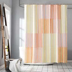 a bathroom with a shower curtain that has different colors and patterns on it, along with a ladder in the corner