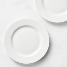 two white plates sitting on top of a table next to each other with one empty plate in the middle