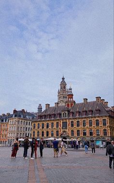 people are walking around in front of an old building with a clock tower on top