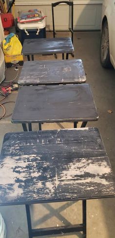 three wooden benches sitting next to each other on top of a garage floor in front of a white car