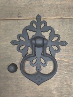 an ornate iron door handle on a wooden surface with a black ball in the foreground