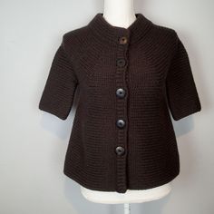 a mannequin wearing a brown knitted cardigan with buttons on the front