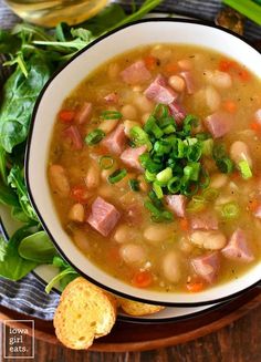 a bowl of ham and bean soup with bread on the side