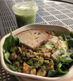 a salad with bread and dressing in a bowl next to a green smoothie drink