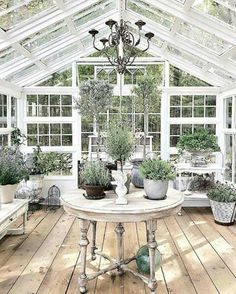 a room filled with lots of potted plants inside of a glass roofed building