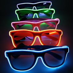 three neon glasses sitting next to each other on top of a black surface with one glowing in the dark