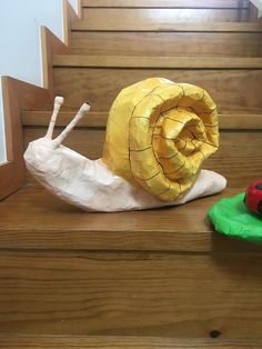 a paper mache snail sitting on top of some stairs