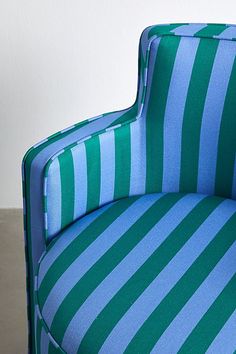 a blue and green striped chair sitting on top of a floor next to a wall