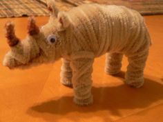 a stuffed animal that looks like a rhinoceros is standing on the floor with its head down and eyes wide open