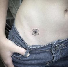 a woman's stomach with a small flower tattoo on her left side ribcage