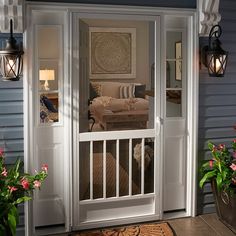 an open door leading to a living room and bedroom area with potted plants on the front porch