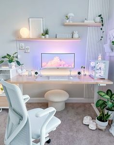 a white desk with a computer monitor and keyboard on it in front of a plant