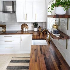 a kitchen with white cabinets and wood counter tops, along with a wooden cutting board