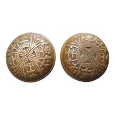 two antique brass door knobs with intricate designs on the front and back sides, one is