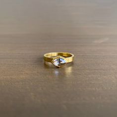 a close up of a gold ring on a wooden table with a white diamond in the center