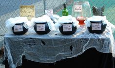 a table topped with lots of bottles of wine next to a chain link fence covered in netting