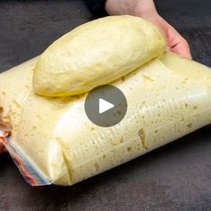 a person holding a bag of bread on top of a black surface with a video screen