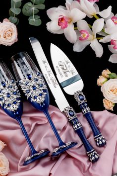 three silver and blue utensils sitting next to flowers