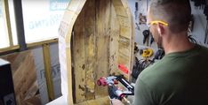 a man working on a wooden door in a workshop with tools and equipment around him