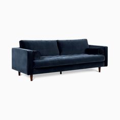 a blue velvet couch with wooden legs and arm rests on an isolated white background,