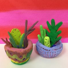 two clay pots filled with plants on top of a white table next to a pink wall