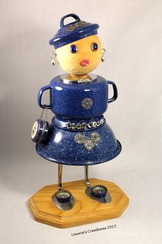 a blue and yellow figurine is standing on top of a wooden stand with two bells