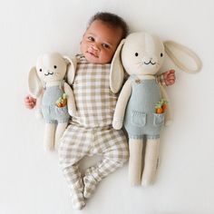 a baby laying next to two stuffed animals