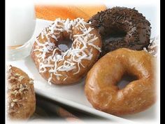 there are four different types of donuts on the plate with a glass of milk