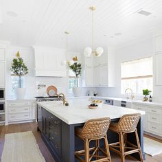 a large kitchen with two stools next to an island