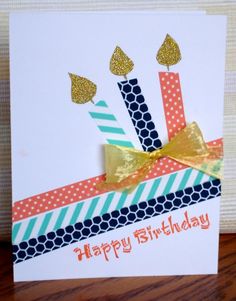 a birthday card with candles on it and gold ribbon around the top, sitting on a table