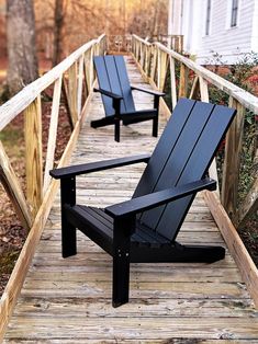 two black adirondack chairs sitting on a wooden deck