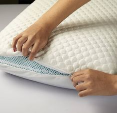 a woman is holding the pillow on top of her bed and pulling it out with her hands