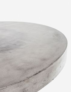 a round concrete table sitting on top of a white floor