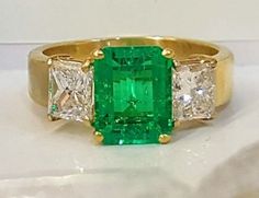 GORGEOUS 18K yellow gold  emerald  ring  NATURAL  GREEN COLOMBIA Emerald ring center emerald shape natural treated green emerald weight 2.05ct.size 9x6.7nice vivid  green color ,clean, very lively ,nice cut .very sparklyside two natural  princess cut diamonds total weight 1.45ct H-SI1Ring SIZE 6.5Retail value $15,500 net.Cert Appraisal available Fine Jewelry Green Radiant Cut Diamond Ring, Green Radiant Cut Diamond Ring Fine Jewelry, Green Radiant Cut Diamond Ring, Fine Jewelry Green Princess Cut Diamond Ring, Green Princess Cut Diamond Ring In Fine Jewelry Style, Green Princess Cut Diamond Ring Fine Jewelry, Green Princess Cut Diamond Ring, Green Diamond Ring With Radiant Cut And Prong Setting, Emerald Cut Green Diamond Ring With Prong Setting