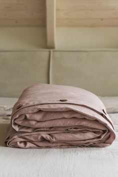 an unmade bed with pink sheets on top of it and a white headboard in the background