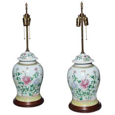 two white vases with flowers on them are next to each other and one is holding a lamp