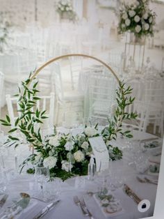 the table is set with white flowers and greenery for an elegant wedding reception or special event