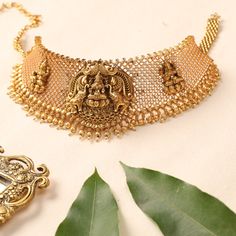 Description A unique take on traditional nakshi temple jewelry, this Ishwari choker set is crafted with the Goddess Lakshmi and elephant motifs at the center with an antique gold-plated base. This intricately crafted modern choker adds a dash of shine to your festive wear accessory. Details & Specifications: Materials used : Brass Alloy with Antique Gold Plating Weight – Choker 89 gm, Earrings 26 gm Length – Choker 18 cm, Earrings 5 cm Make it custom Want to make it a custom choker? Sure! Reach Gold Antique Choker, Traditional Brass Choker, Traditional Gold Cutdana Choker, Bohemian Gold Choker With Meenakari, Gold Hand-set Temple Jewelry Choker, Antique Choker, Temple Jewelry, Goddess Lakshmi, Festive Wear