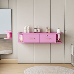 a pink shelf with some bottles on it in front of a mirror and a rug