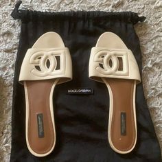 In Beige Beige Flat Sandals For Evening, Luxury Cream Mules, Designer Flat Slides For Beach, Designer Slip-on Sandals With Branded Insole, Elegant Beige Leather Slides, Elegant Round Toe Slides For Vacation, Elegant Flat Mules For Vacation, Elegant Vacation Mules With Removable Insole, Designer Leather Slides For The Beach