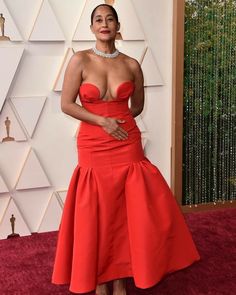 an image of a woman in red dress on the oscars red carpet with her hands behind her back